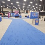 Wide view of the exhibition hall with blue carpet walkways and branded exhibit areas installed for the Rotary International Convention